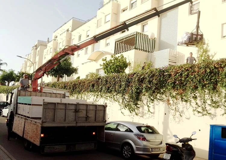 Camión pluma en Fuengirola con carga elevada de palets de pladur
