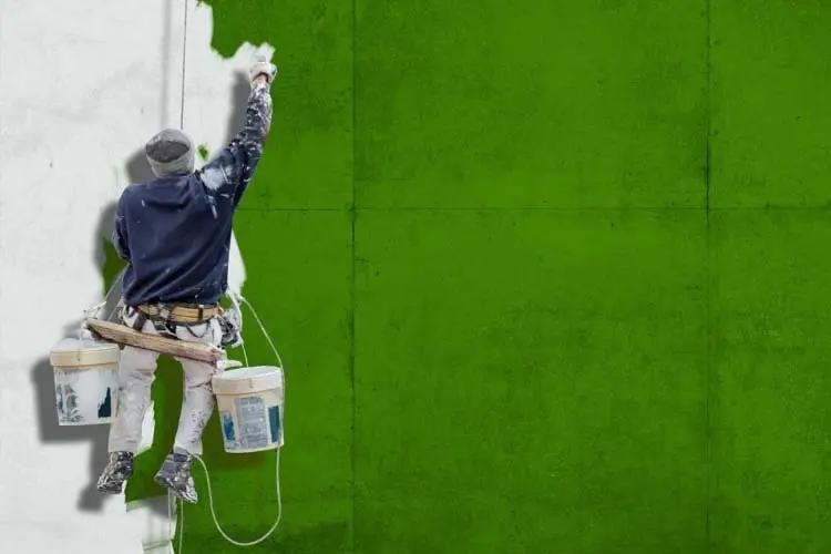 Pintor-pintando- una fachada de un edificio-de-color-verde-Profesionales Málaga