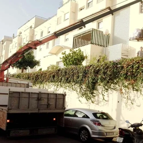 Camion grua con carga elevada de palets de yeso Camión pluma en Fuengirola con carga elevada de palets de pladur